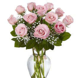 Bouquet of light pink roses with white filler flowers in a clear glass vase