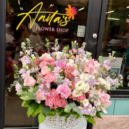 Large pink and lavender mixed flower arrangement in a white basket