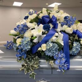 White and blue funeral spray on a casket with ribbon