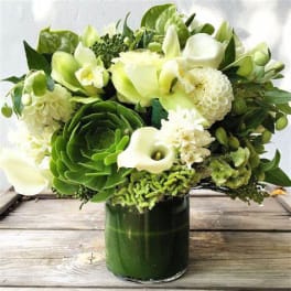Green and white floral arrangement in a glass vase
