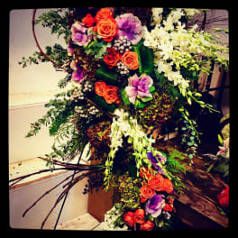 Large floral spray with orange roses, purple blooms, and white orchids
