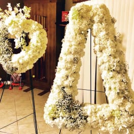 Large white floral wreaths on black stands in an indoor venue