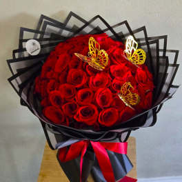 Bouquet of red roses wrapped in black paper with butterfly decorations