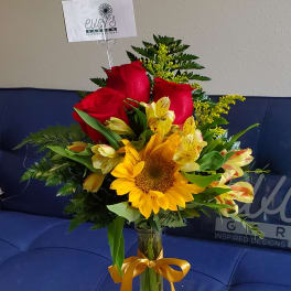 Bouquet of red roses and yellow flowers in a glass vase with a ribbon