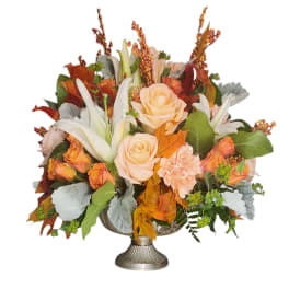 Autumn floral arrangement with peach roses and white lilies in a silver vase
