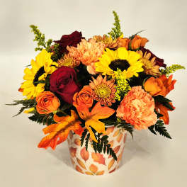 Fall bouquet of sunflowers, roses, and mums in a leaf-patterned vase