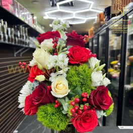 Red and white roses arranged in a metal vase with green pom-pom accents.