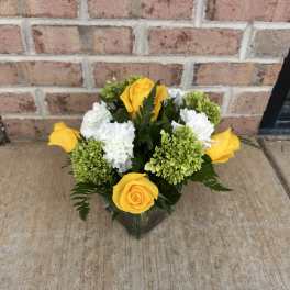 Yellow roses and white carnations in a glass vase