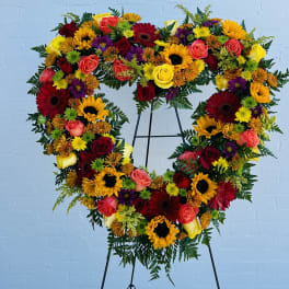 Heart-shaped floral arrangement with roses, sunflowers, and mixed blooms on an easel