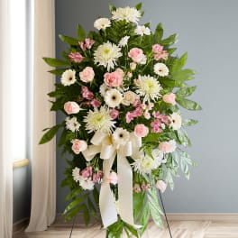 Standing floral spray with pink roses, white daisies, and a cream ribbon