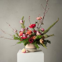 Tall mixed bouquet of pink and red roses in a striped ceramic vase