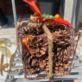 Wire basket filled with pinecones and tied with rope and red ribbon