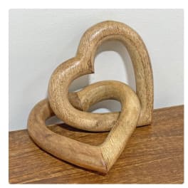 Two interlocking wooden heart sculptures on a tabletop