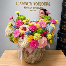 Large mixed flower arrangement in a woven basket with pink and yellow blooms