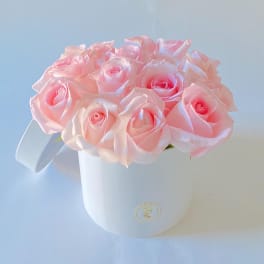 Pink roses arranged in a white round box with a ribbon