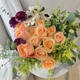 Bouquet of peach and purple roses with white flowers and greenery