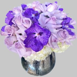 Lavender roses and purple orchids in a metallic vase