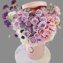Lavender and pink rose bouquet in a pink hatbox with white flowers