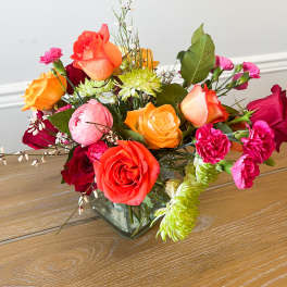 Mixed bouquet of roses, carnations, and mums in a glass vase