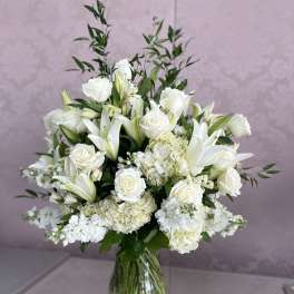 White roses and lilies arranged in a clear glass vase