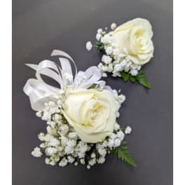 Two white rose boutonnieres with baby's breath and ribbon