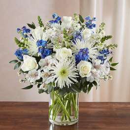 White and blue mixed bouquet in a clear glass vase