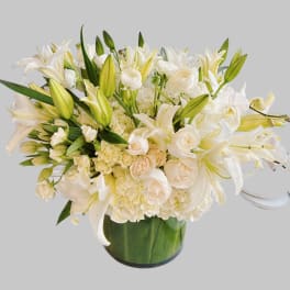 White lilies and roses arranged in a green glass vase