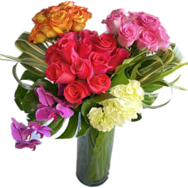 Mixed bouquet of roses, orchids, and hydrangeas in a glass vase