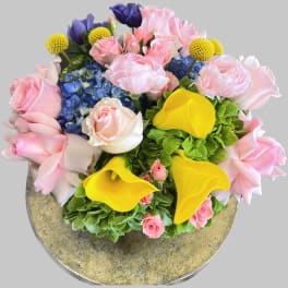 Bouquet of pink roses, blue hydrangeas, yellow calla lilies, and yellow button flowers