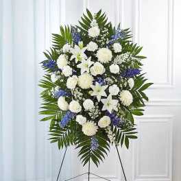 Standing funeral spray with white lilies, roses, and blue flowers