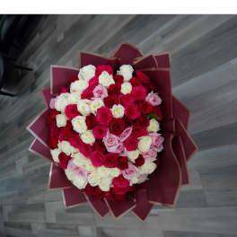 Large bouquet of red, pink, and white roses wrapped in burgundy paper
