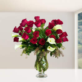 Bouquet of red roses and white calla lilies in a glass vase