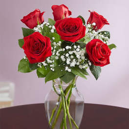 Red roses with baby's breath in a clear glass vase