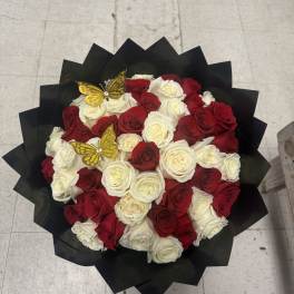 Bouquet of red and white roses wrapped in black paper with gold butterfly picks