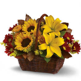 Basket arrangement with yellow lilies, sunflowers, and red daisies