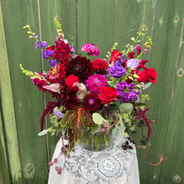 Mixed bouquet of red, purple, and pink flowers in a glass vase