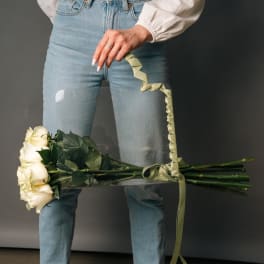 Person holding a bouquet of white roses with a ribbon