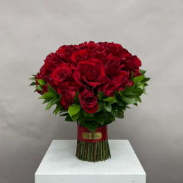 Bouquet of red roses with green foliage tied at the stems