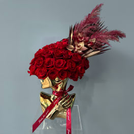 Red rose arrangement in a gold bust vase with a red ribbon
