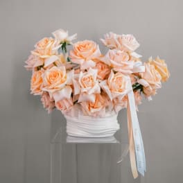 Peach roses arranged in a white vase with a Dior ribbon