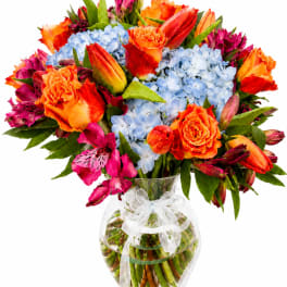Bright mixed bouquet in a clear glass vase with a white ribbon bow
