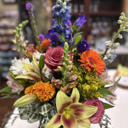 Mixed bouquet with pink roses, orange gerberas, and lilies in a plaid wrap