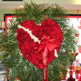 Heart-shaped red rose arrangement with a red ribbon and white rose accents