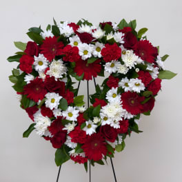 Heart-shaped floral wreath with red and white flowers on a stand