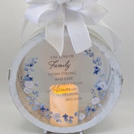 White memorial lantern with a large bow and a lit candle inside