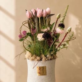 Pink tulips and mixed flowers arranged in a white vase