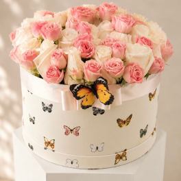 Pink and white roses in a round hat box with butterfly decorations