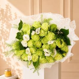 Bouquet of lime green and white flowers wrapped in white lace paper