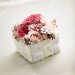 Pink and white rose arrangement on a pearl-decorated box with two rings