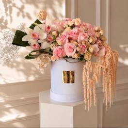 Pink roses and white orchids arranged in a white hat box